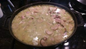 Close-up photograph of gumbo stew cooking in a large cast iron pot on a stovetop